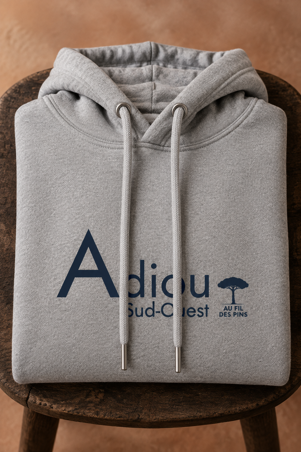 Sweat Adiou gris chiné plié sur un tabouret en bois